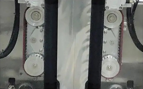 Detail balicího stroje s klínovými sáčky - Synchronizované kolo pro stahování sáčků